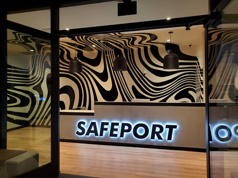 Indoor building signs like this halo-lit channel letters sign and custom wall graphics for Safeport in Oxnard, CA, help bring in new customers.