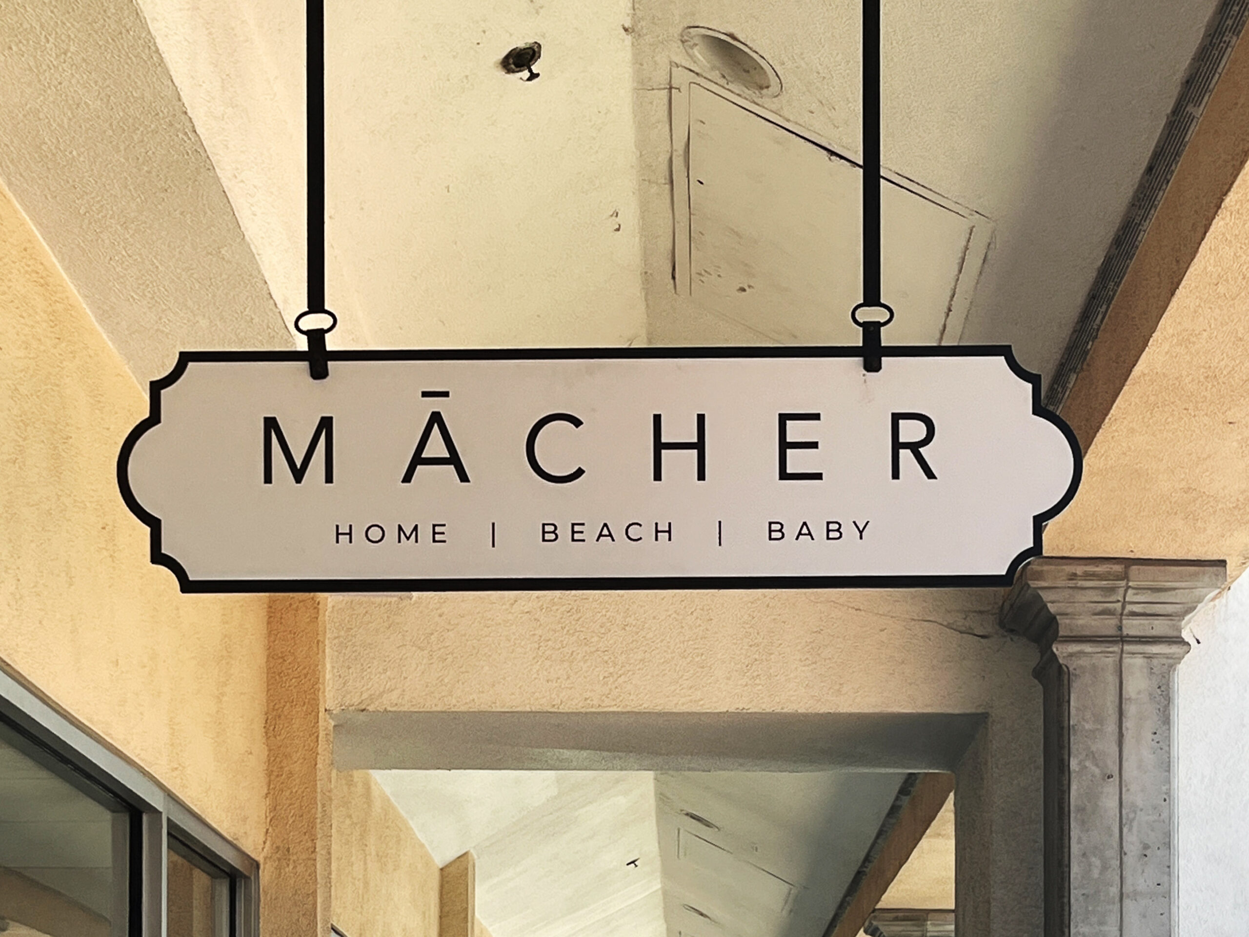 Mācher – Hanging signs are more commonly called blade signs and are great for shopping malls with high pedestrian traffic.