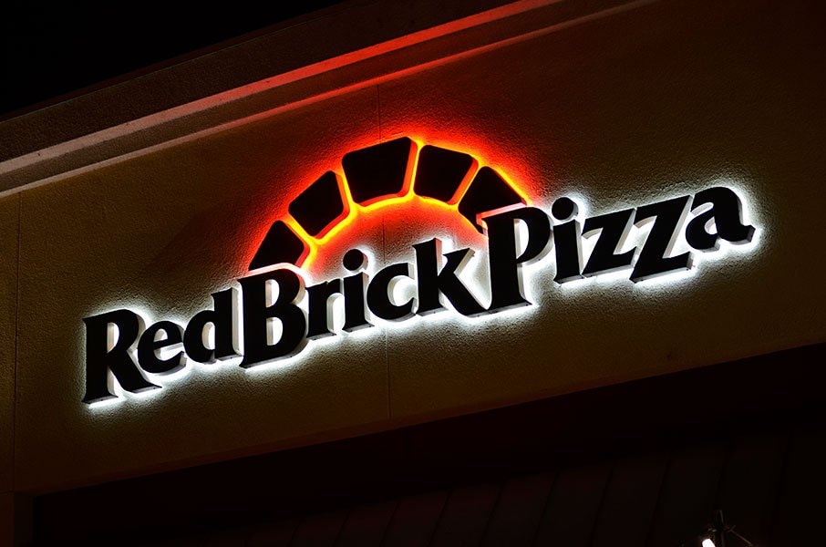 Red Brick Pizza illuminated halo-lit channel letter sign at night.