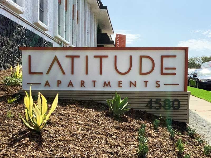 Latitude Apartments in San Diego featuring dimensional lettering mounted to a smooth stucco face with a stone base and integrated address panel.
