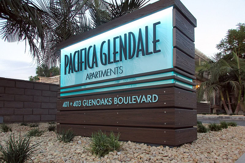 Pacifica Glendale Apartments monument sign featuring high-density urethane (HDU) fabricated with a realistic wood-grain finish, dimensional lettering, and integrated LED illumination.