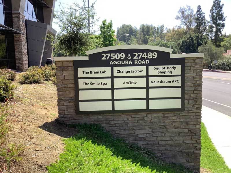Multi-tenant monument sign for 27509 & 27489 Agoura Road in Agoura Hills, CA featuring a stone masonry base with changeable tenant panels and integrated address identification.