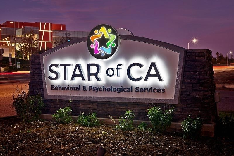 Illuminated monument sign for Star of CA in Ventura featuring halo-lit channel letters, dimensional lettering, an internally lit cabinet face, LED lighting, and integrated ground illumination set within a stone and masonry base.