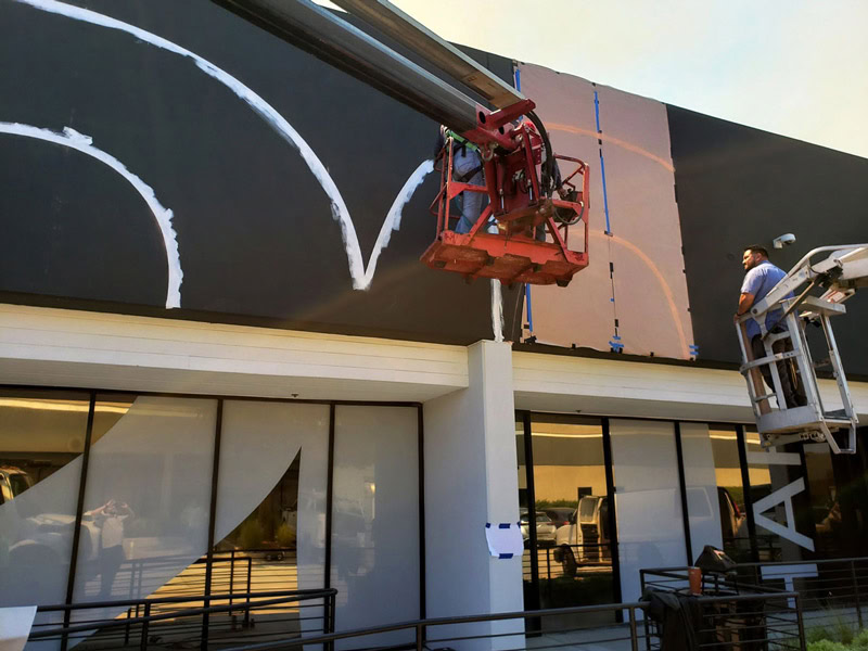 Crew painting a large architectural graphic on the 20 Bloc Biopharma building.
