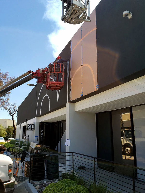 Crew laying out a hand-painted architectural graphic on the 20 Bloc Biopharma building.