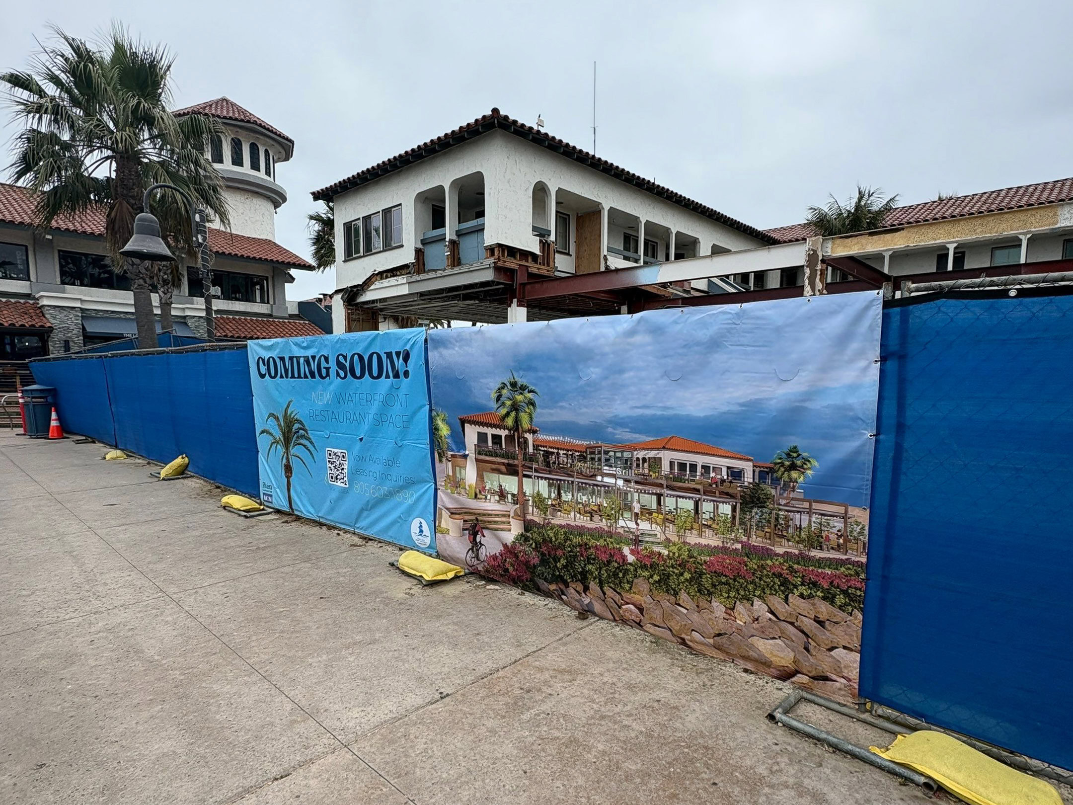 Temporary construction fence banners featuring a coming-soon announcement and architectural rendering of a waterfront restaurant at Ventura Harbor in Ventura, CA.
