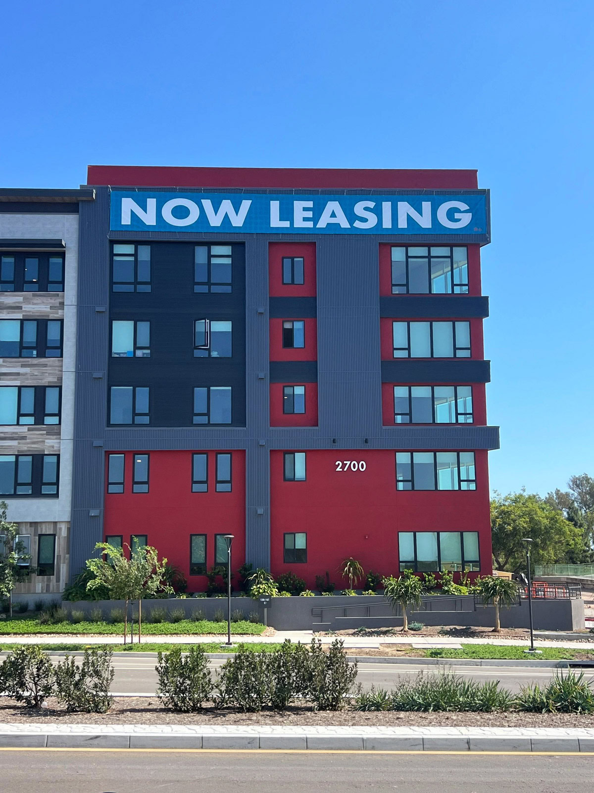 Large temporary NOW LEASING building banner installed at Panorama Riverpark in Oxnard, CA.